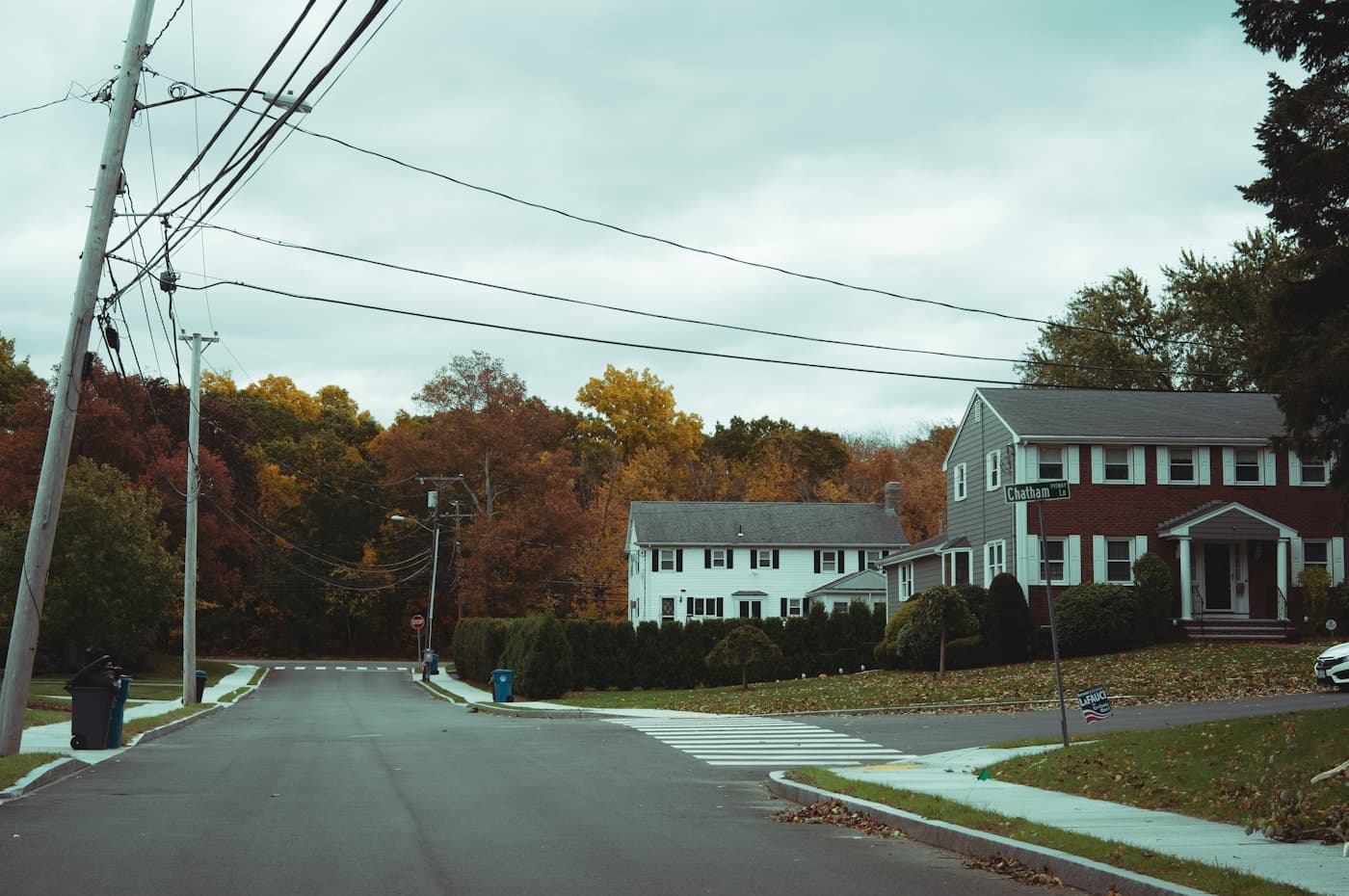 A quiet Pittsburgh-area neighborhood street in autumn, lined with classic family homes and warm fall colors.